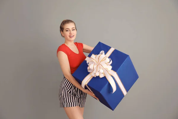 Gyönyörű fiatal nő, nagy ajándék doboz színes háttérrel — Stock Fotó