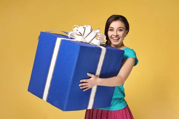 Beautiful young woman with big gift box on color background — Stock Photo, Image