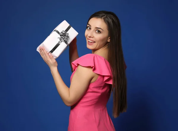 Belle jeune femme avec boîte cadeau sur fond de couleur — Photo