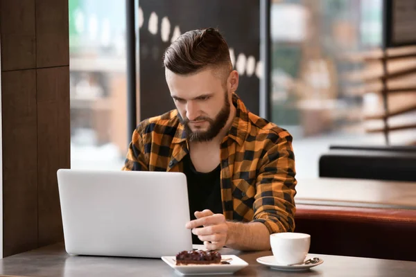 Молодой фрилансер с ноутбуком работает в кафе — стоковое фото