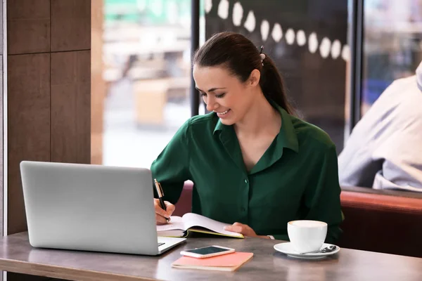 Young freelancer with laptop working in cafe — Stock Photo, Image