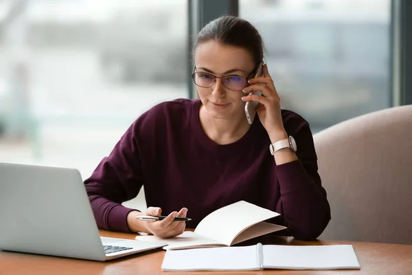 Junge Freiberuflerin mit Handy und Laptop im Café — Stockfoto