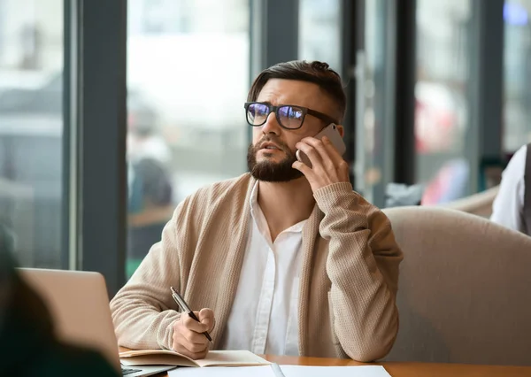 Giovane freelance con cellulare e laptop che lavora nel caffè — Foto Stock