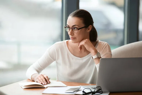 Junge Freiberuflerin mit Laptop arbeitet im Café — Stockfoto