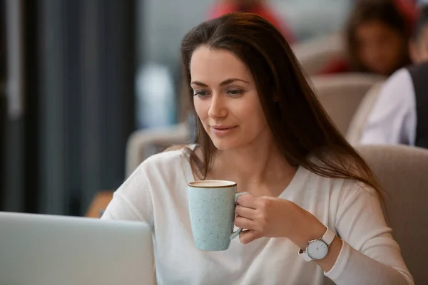 Junge Freiberuflerin mit Kaffee und Laptop im Café — Stockfoto