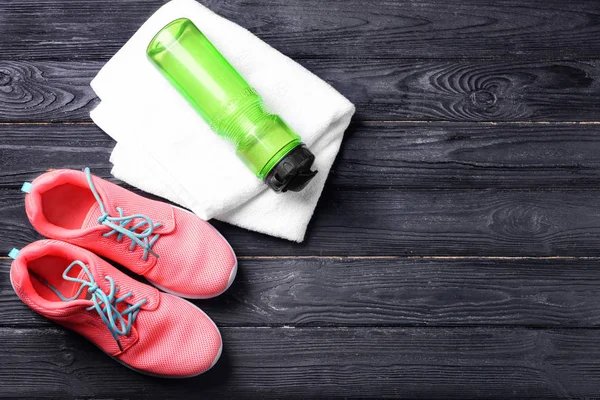 Επίπεδη lay σύνθεση με πάνινα παπούτσια, μπουκάλι νερό και πετσέτα για ξύλινο υπόβαθρο. Γυμναστήριο προπόνηση — Φωτογραφία Αρχείου