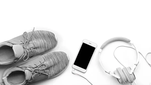 Samenstelling met sneakers, smartphone en koptelefoon op witte achtergrond, bovenaanzicht. Training van de gymnastiek — Stockfoto