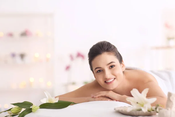 Jonge vrouw ontspannen op massagetafel op spa salon — Stockfoto