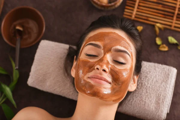 Young woman with face mask relaxing on massage table at spa salon — Stock Photo, Image