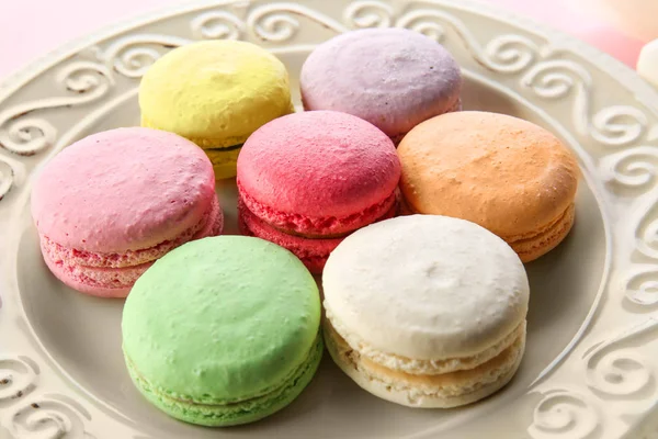 Teller mit leckeren Macarons auf farbigem Hintergrund — Stockfoto