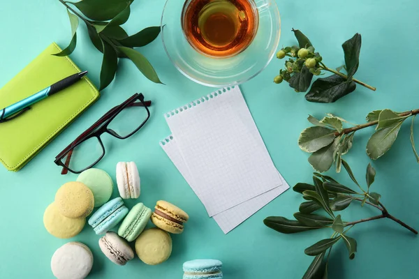 马卡龙, 杯茶, 纸和眼镜在色彩背景上的平躺组合 — 图库照片