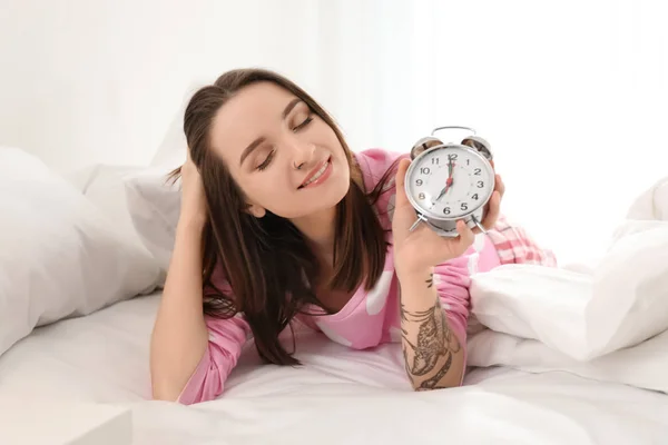 Young woman with alarm clock in bed. Early morning — Stock Photo, Image