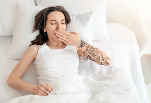 Young beautiful woman yawning on bed in morning — Stock Photo, Image