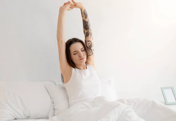 Young beautiful woman stretching on bed in morning — Stock Photo, Image