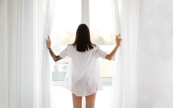 Young beautiful woman standing near window in morning — Stock Photo, Image