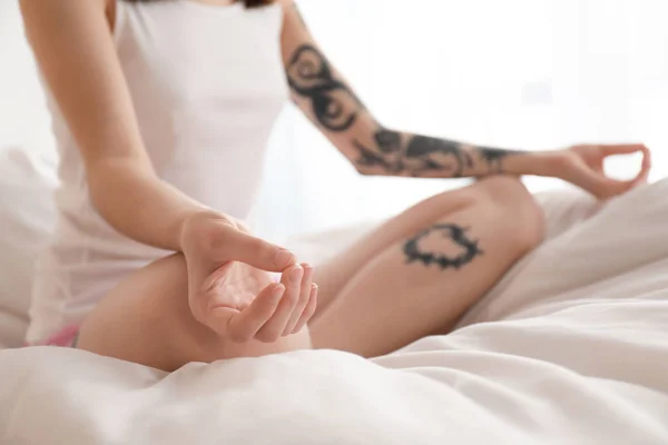 Young woman practicing yoga on bed in morning — Stock Photo, Image