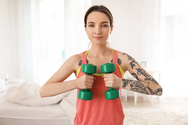 Beautiful young woman doing exercises with dumbbells in morning — Stock Photo, Image