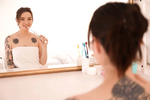 Mladá žena v ručník čistit zuby blízko doma zrcadlo. Ranní vstávání — Stock fotografie
