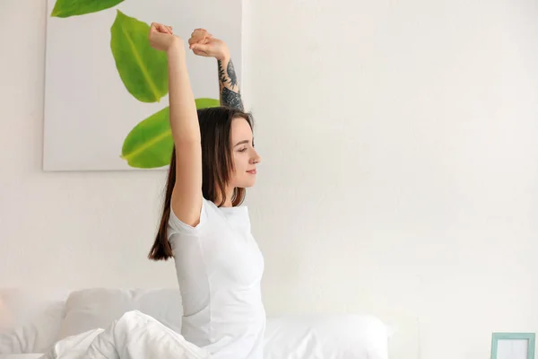 Mooie jongedame die zich uitstrekt op bed in de ochtend — Stockfoto