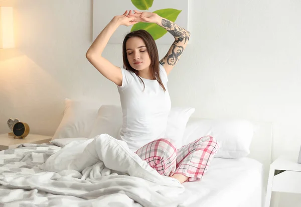 Young beautiful woman stretching on bed in morning — Stock Photo, Image