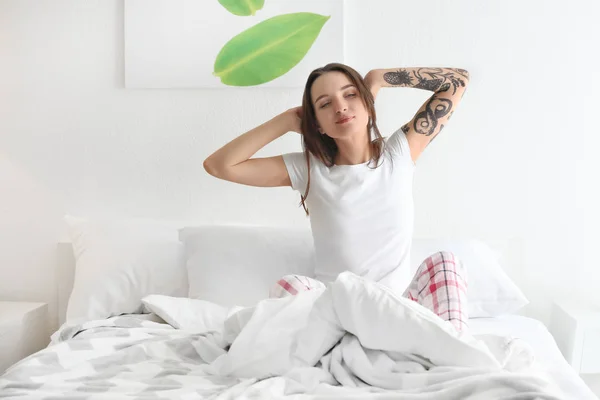 Mooie jongedame die zich uitstrekt op bed in de ochtend — Stockfoto