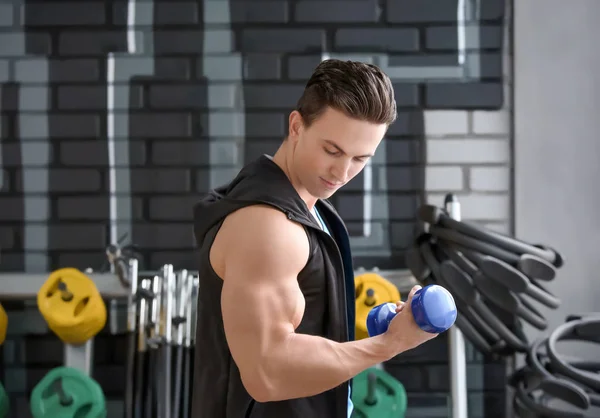 Young man training with dumbbell in modern gym — Stock Photo, Image
