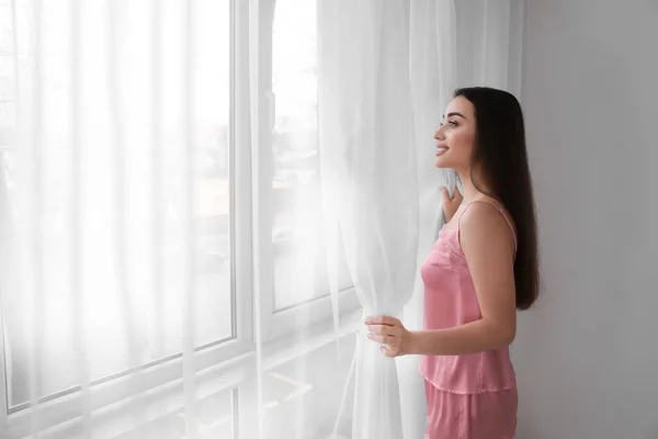 Young beautiful woman standing near window in morning — Stock Photo, Image