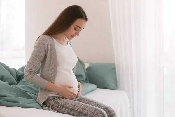 Beautiful pregnant woman sitting on bed in morning — Stock Photo, Image