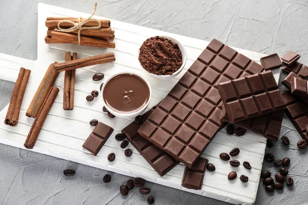 Flat lay composition with tasty chocolate, coffee beans and cinnamon sticks on wooden board — Stock Photo, Image