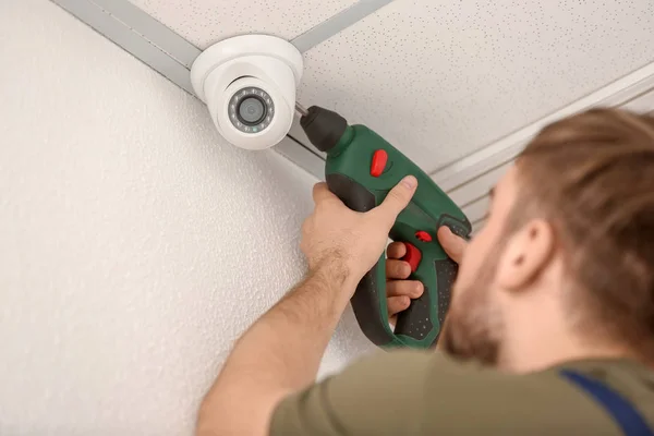 Electrician installing security camera indoors — Stock Photo, Image