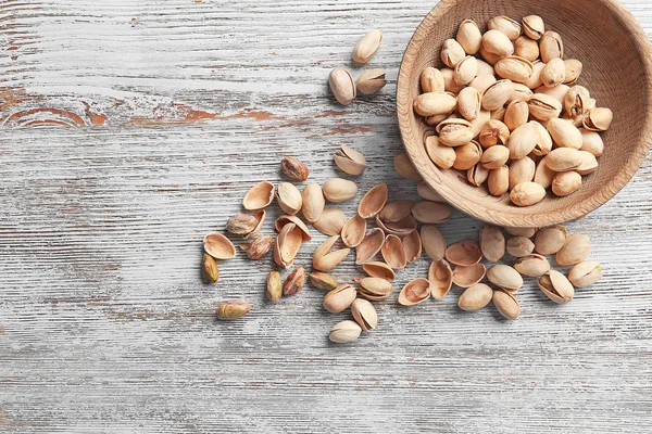 Bowl with pistachio nuts on wooden background — Stock Photo, Image