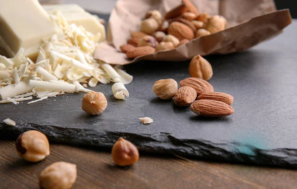 Schieferteller mit weißen Schokoladenlocken und Nüssen auf dem Tisch — Stockfoto