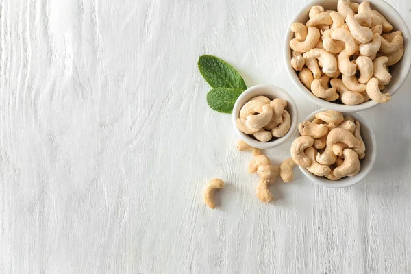 Bowls with tasty cashew nuts on wooden table — Stock Photo, Image