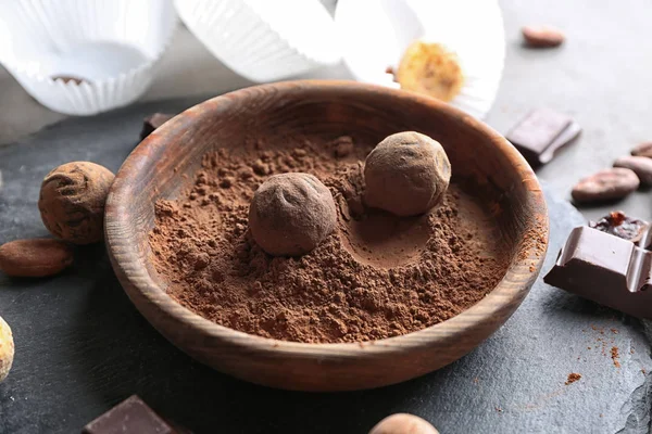 Dulces de chocolate en tazón con cacao en polvo en la mesa —  Fotos de Stock