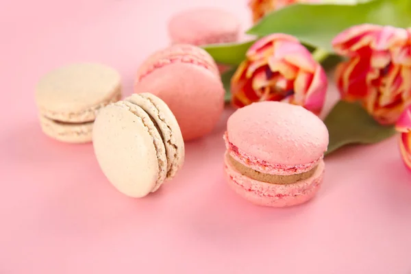 Delicious macarons and flowers on color background — Stock Photo, Image