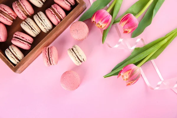 Köstliche Macarons und Blumen auf farbigem Hintergrund — Stockfoto