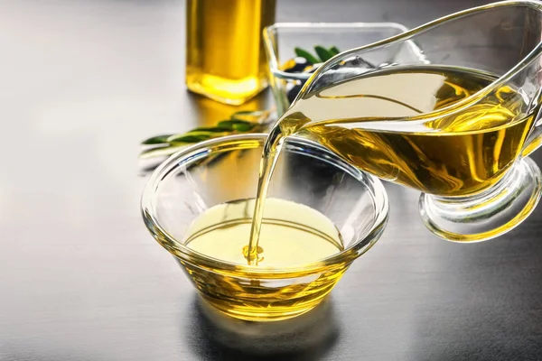 Verser l'huile d'olive dans un bol en verre sur la table, gros plan — Photo