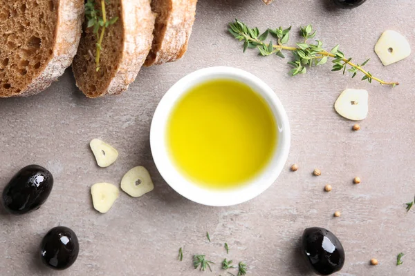 Miska oleju, czarne oliwki i chleb na szarym tle, widok z góry — Zdjęcie stockowe