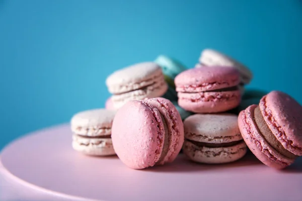 Suporte de sobremesa com macarons saborosos no fundo de cor — Fotografia de Stock