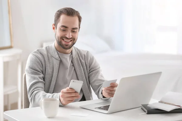 Male freelancer with smartphone and business card at workplace — Stock Photo, Image