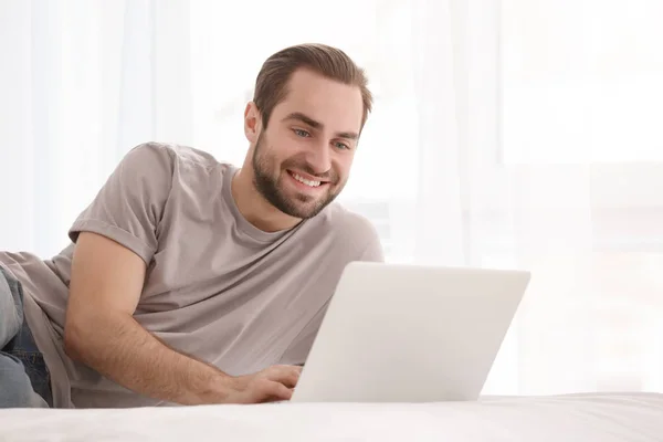 Male freelancer working with laptop in bed — Stock Photo, Image