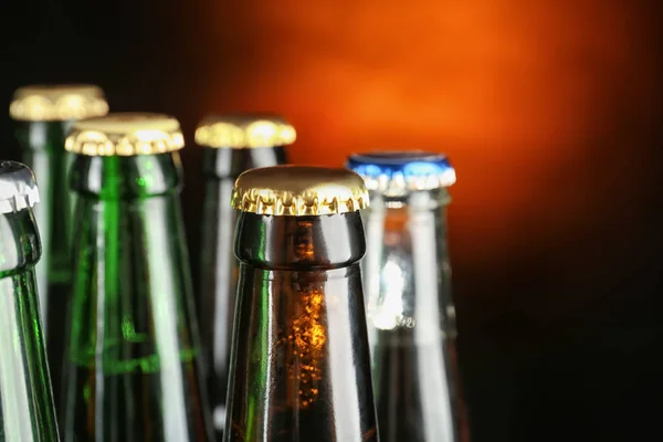 Cerveja fresca em garrafas de vidro no fundo escuro — Fotografia de Stock