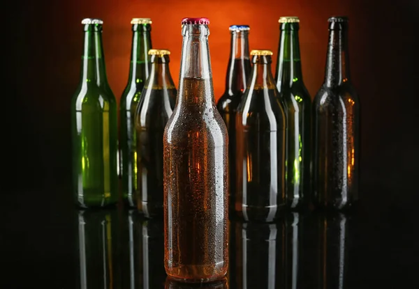 Свежее пиво в стеклянных бутылках на темном фоне — стоковое фото