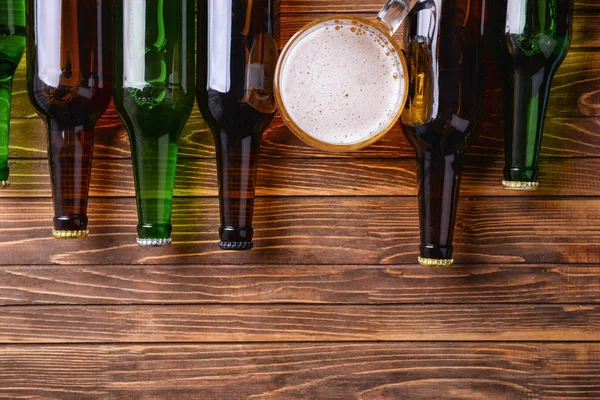 Свіже пиво в скляних пляшках і кухоль на дерев'яному фоні — стокове фото