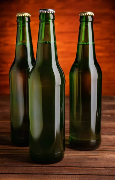 Cerveza fresca en botellas de vidrio sobre mesa sobre fondo oscuro — Foto de Stock