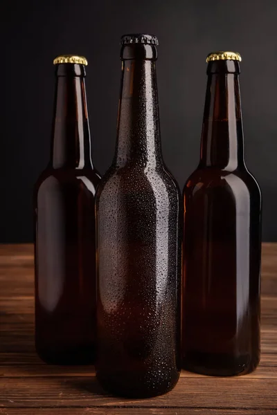 Fresh beer in glass bottles on table against dark background — Stock Photo, Image