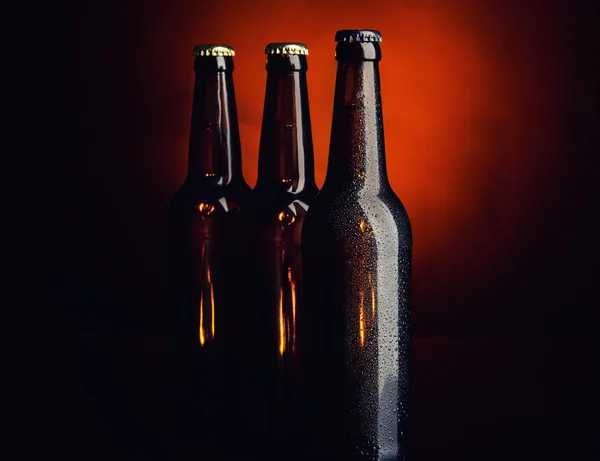 Cerveza fresca en botellas de vidrio sobre fondo oscuro — Foto de Stock