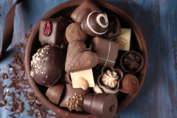 Plate with different tasty chocolate candies on wooden table — Stock Photo, Image