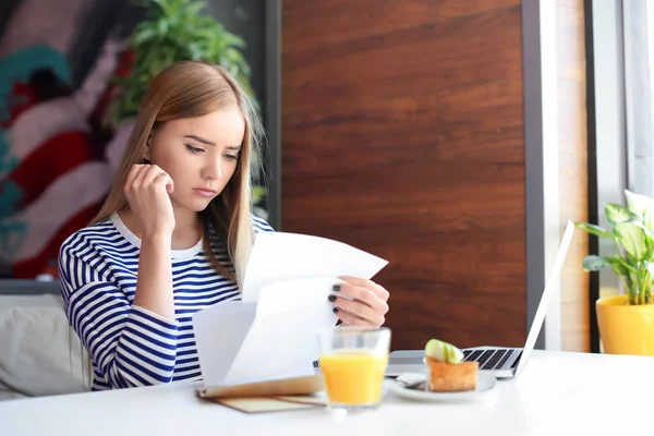 Mujer joven leyendo carta en la mesa en la cafetería. Entrega de correo —  Fotos de Stock