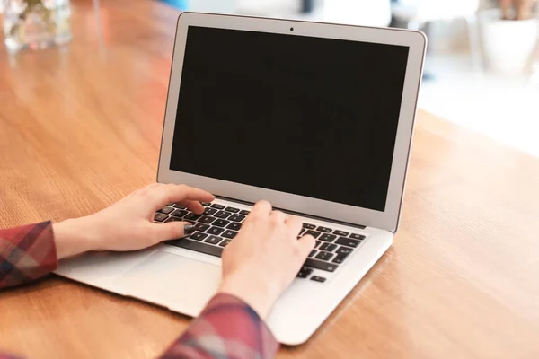 Jovem mulher usando laptop à mesa no café — Fotografia de Stock